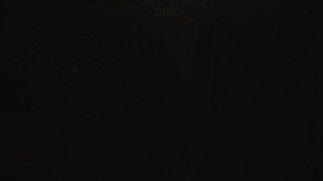 Moisture and streaks on car window while passing through tunnel, blurred lights sliding across glass during night drive inside moving vehicle