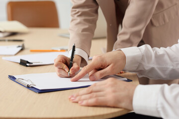 Business mediator with client writing in clipboard on table, closeup