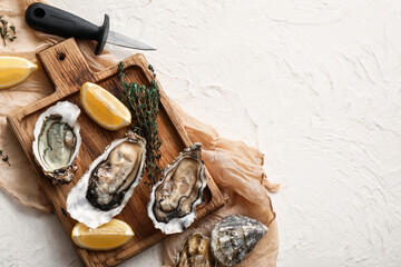 Wooden board with delicious fresh oysters, thyme and lemon on white background © Pixel-Shot