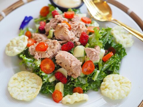 A vegetable salad with tuna is placed on a plate on the dining table. It looks appetizing and delicious. It's a healthy food.