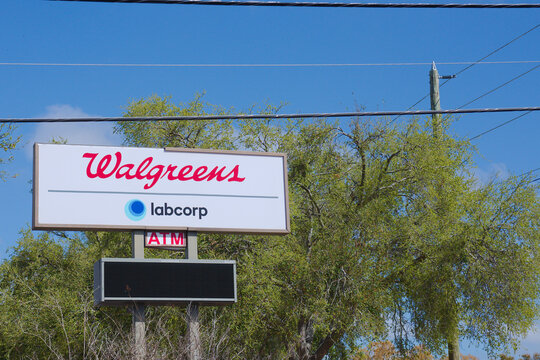 Walgreens Sign With Labcorp Logo And ATM On A Sunny Day Near Trees. Editorial Use Only, March 4, 2026 St. Petersburg, FL USA. Retail pharmacy, medical testing services and roadside commercial branding