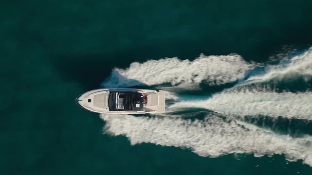 Aerial top-down drone view of a speedboat cruising across deep blue ocean water in Miami, Florida leaving a white wake trail.