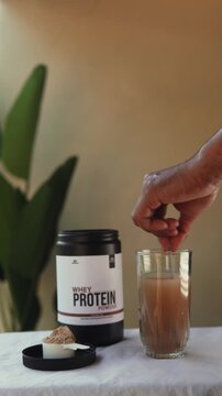 Person mixing whey protein drink in a glass