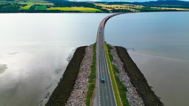 Wide drone view of Tongue Causeway crossing the Kyle of Tongue in the Scottish Highlands, showcasing remote infrastructure within a dramatic coastal landscape.