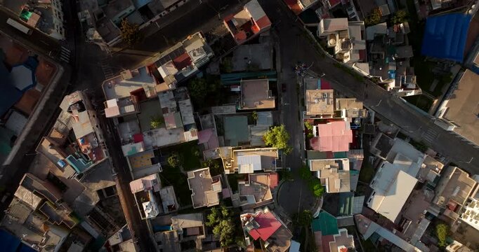Cinematic top-down drone view of rooftops and streets in Arequipa, Peru at golden hour. Dense urban neighborhood pattern with colorful buildings and long shadows in South America