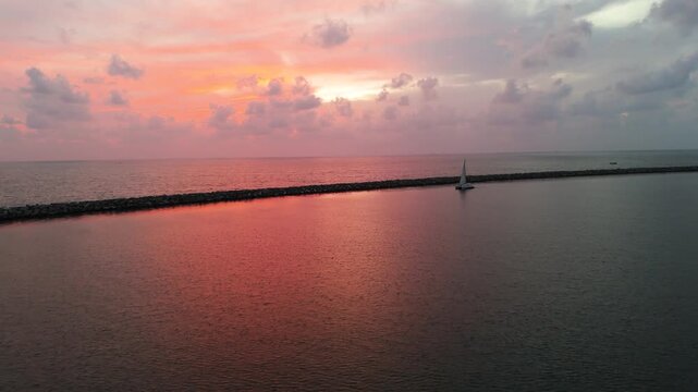 4K beautiful coastal evening showing a serene ocean horizon and a boat cruising along a rocky jetty