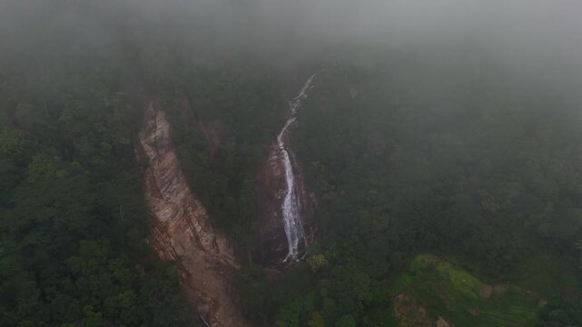 4K cinematic nature scene of a majestic waterfall flowing through a pristine misty tropical rainforest