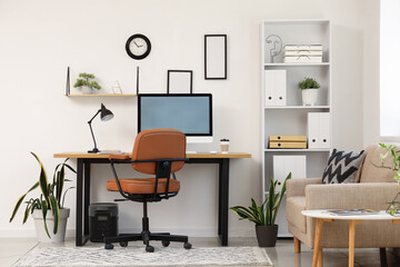Interior of light office with workplace, shelf unit and sofa
