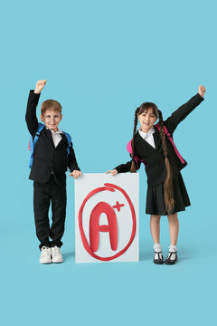 Happy pupils holding poster with a-plus grade on blue background