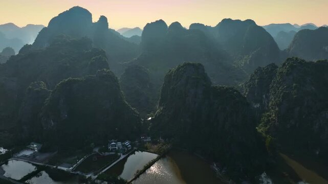 Aerial view of Tam Coc, Vietnam, showcasing the serene landscape. Limestone karsts rise amidst rice paddies and waterways, creating a tranquil scene in Ninh Binh province.