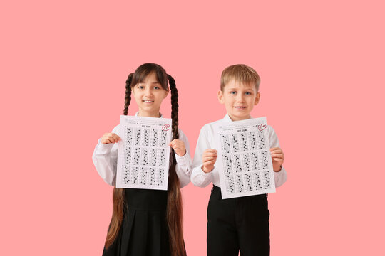 Happy little pupils with good results of school tests on pink background