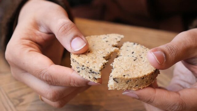 Hands breaking a round cookie in a cafe setting