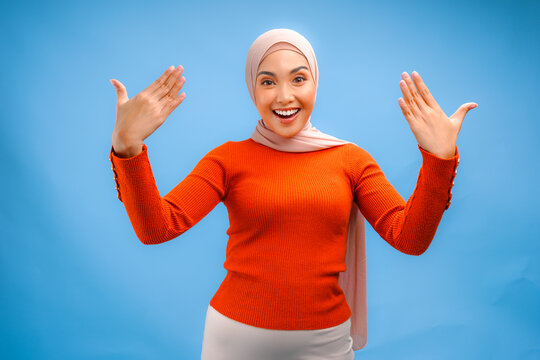 Excited Asian Muslim woman wearing headscarf veil hijab gesturing welcome or inviting.
