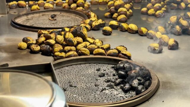 Traditional roasted chestnuts cooking on a hot metal stove. Popular winter street food in Istanbul. Close-up of hot chestnuts with steam, authentic Turkish outdoor snack.