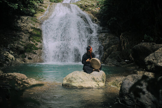 Acehnese Man Playing Traditional Rapai Drum at Waterfall &ndash; Cultural Music Performance in Tropical Nature, Indonesian Heritage and Travel Culture Concept