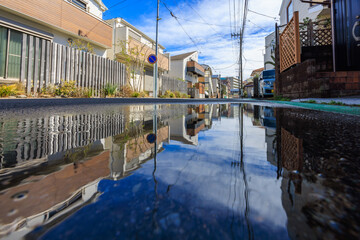 水たまりに青空と住宅街が反射する雨上がりの風景