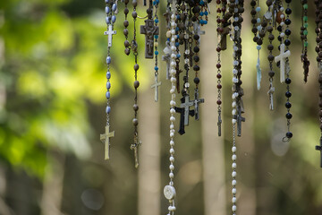 Hanging Rosaries and Crosses in Forest Light, Religious Prayer Beads and Devotional Symbols