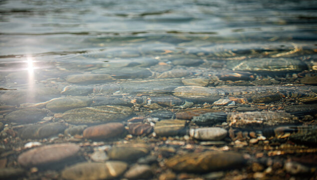 Clear transparent water flowing over smooth river pebbles in horizontal framing