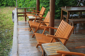 Fototapeta premium A row of empty wooden lounge chairs sits on a wet riverside deck, waiting for guests to come and relax by the water.