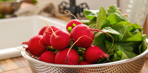 Naklejka premium Colander with fresh radish on table in kitchen