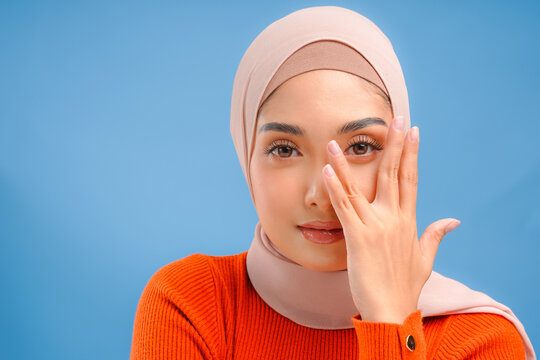 Close up of chic Asian Muslim woman wearing hijab and makeup is posing to the camera.