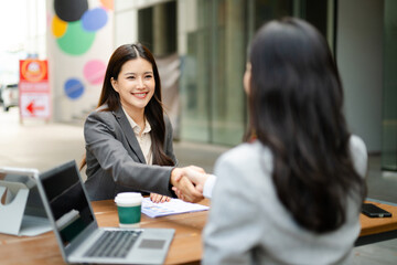 Businesswomen shaking hands in corporate office meeting, symbolizing partnership, agreement, teamwork, leadership, success and strategic collaboration.