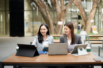 Businesswomen collaborating with laptop and tablet in a modern workspace, representing teamwork, communication, startup planning, leadership and corporate strategy.