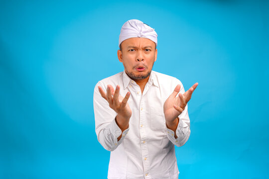 Disgusted young Balinese man wearing Indonesian traditional udeng posing with funny expression.