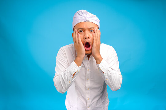 Surprised young Balinese man wearing Indonesian traditional udeng with shocking expression.