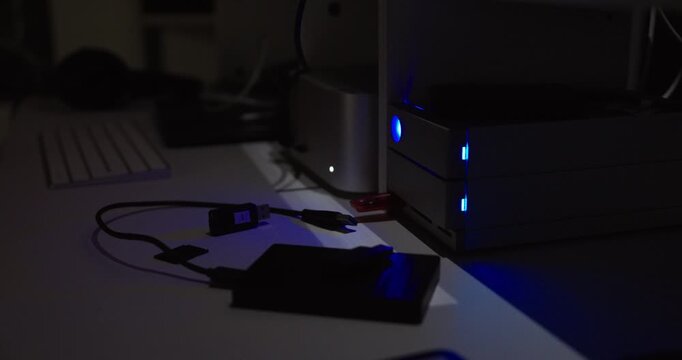 Close-up of a desktop server with blue indicator LEDs and a blinking red light, suggesting data transfer, system activity, or potential error notification in a dark office environment.