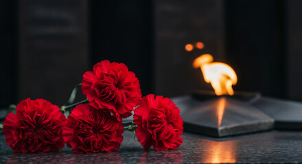 Red carnations at eternal flame memorial symbolizing Victory Day