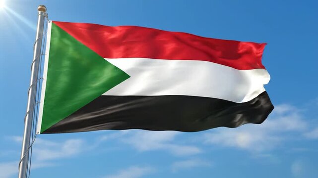 The national flag of Sudan proudly waves in the bright blue sky with sun rays.