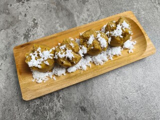 Traditional Indonesian Apem Cake With Palm Sugar and Grated Coconut in Wooden Plate