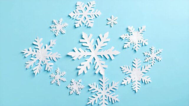White paper snowflakes arranged in a circular pattern on a light blue background