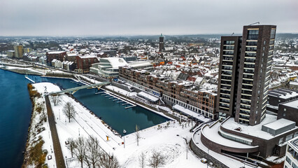 Snowy Venlo town waterfront near Maas river aerial drone view, winter cityscape with rooftops covered with snow, winter weather in Limburg, the Netherlands
