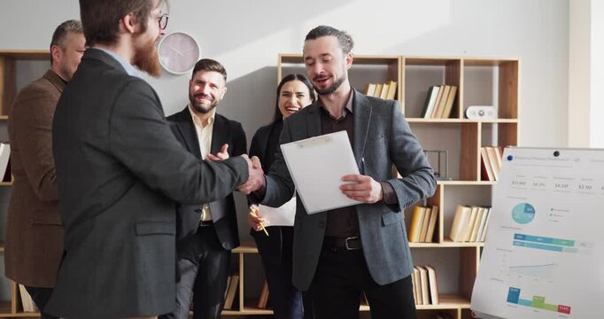 Business team meeting handshake among colleagues. In a modern office, celebrating success, finalizing an agreement after training and showing leadership. Clear message of partnership and trust.