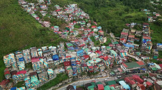 Scenic aerial view of dense hillside settlement of colorful homes along a curved main road - Valley of Colors, Baguio, Philippines
