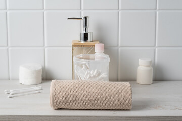 Bathroom shelf with towels and skincare items for daily routines and personal care in a simple setting