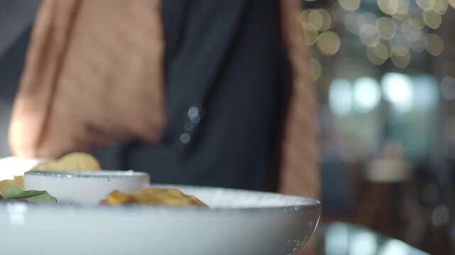 Close up shot of person pouring olive oil on dish at restaurant, adding finishing touch to gourmet meal, dynamic food preparation footage