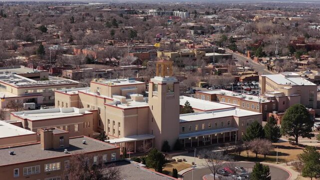 A smooth aerial orbit showcases the unique Southwestern architecture of the New Mexico State Capitol. This 4K perspective highlights the building's circular design and adobe-toned facade.