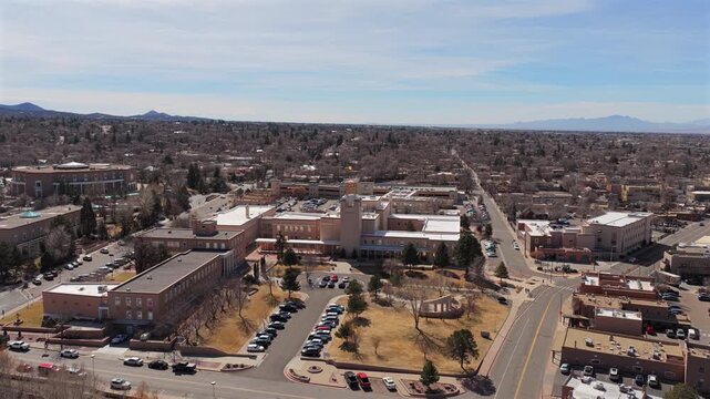A lateral drone movement captures a distant view of the circular Roundhouse building. This 4K shot features the unique adobe-style architecture of downtown Santa Fe against the desert sky.