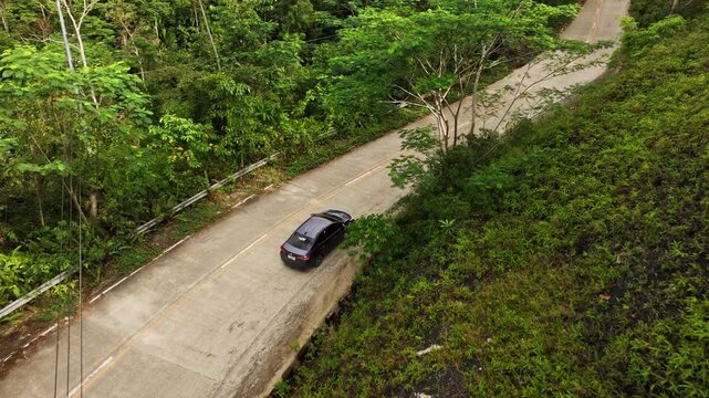 Aerial view of tourists driving through scenic mountain jungle road