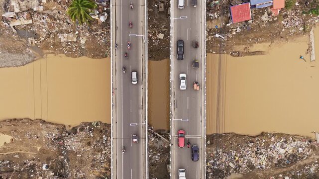 Static Top-down drone view showing urban movement above polluted riverbanks