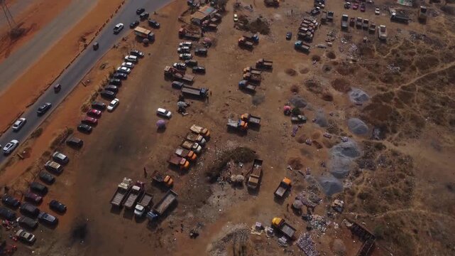 Beautiful aerial of a lot of construction truck heavy vehicles and parked cars alongside a busy highway in Abuja, FCT, Nigeria on a sunny day