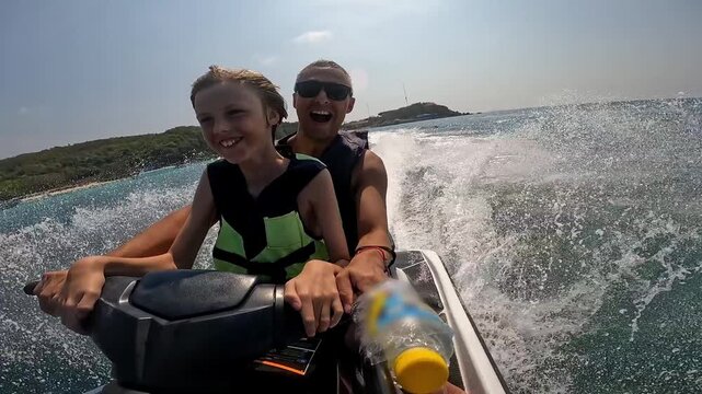 A family jet ski ride &ndash; father and child in life jackets racing across turquoise water, smiles, speed, a foamy wake and an island on the horizon.
