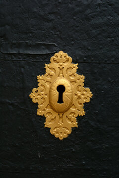 Keyhole. An antique gold-colored lock on an old metal door.	
