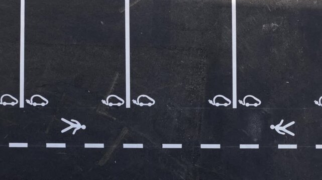 The view shows empty parking spaces designed for electric vehicles. These spaces feature clear markings for electric cars. The setting is a public parking lot during the day.. High quality 4k footage