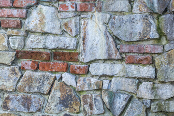 Kamienna ceglana ściana, stary mur z nieregularnych kamieni i czerwonej cegły, rustykalna tekstura tła do projektów.