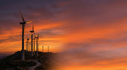 Obraz premium Wind turbines standing on hilltop during sunset with colorful sky Earth Day