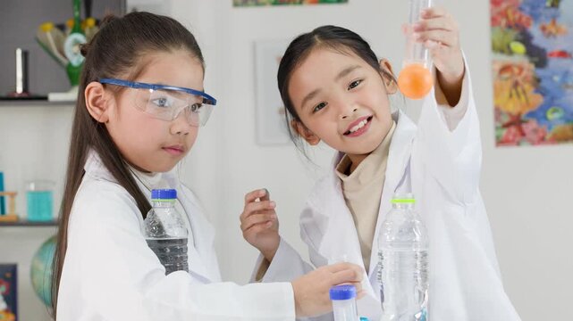 Two Asian Schoolgirls Conduct Bernoulli's Principle Science Experiment with Ping Pong Balls